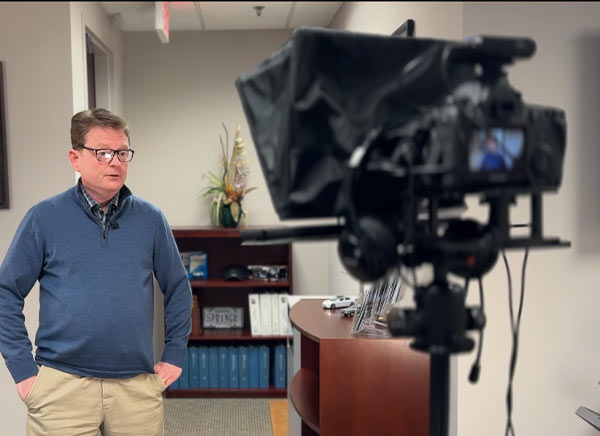 Chris standing infron of the teleprompter shooting a video